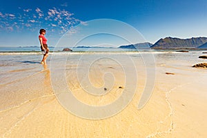 Woman walking on sandy beach, Lofoten Norway