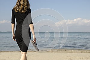 Woman walking on the shore of the beach towards the sea