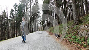 Woman walking with small black dog in the woods