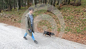 Woman walking with small black dog in the woods