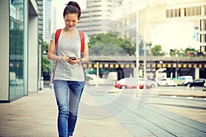 woman walking with smart phone in modern city