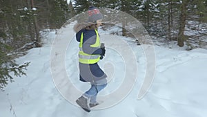 Woman walking in snow covered forest and watching through binoculars