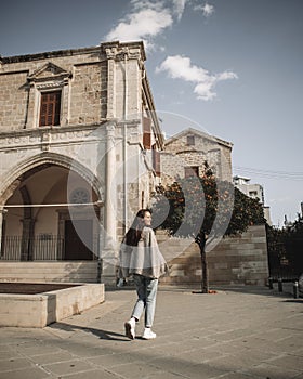 Woman is walking at the square with ancient building and tangerine tree