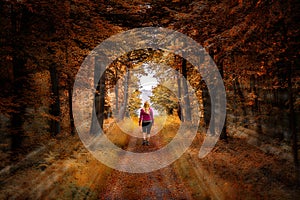 Woman walking on a straight path in a colorful autumn forest photo