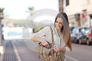 Woman walking on the street and searching in a bag