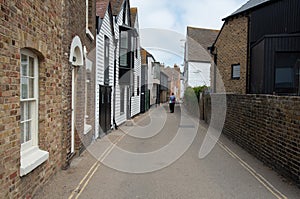 Woman walking in the street Whitstable town Kent. Traditional British houses