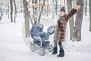 Woman walking with stroller in forest at winter.