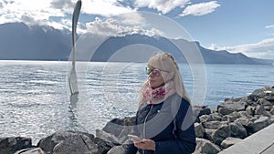 Woman walking on a sunny day in front of a fork sculpture on Lake Geneva in Vevey,