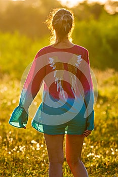 Woman walking at sunset in a green field