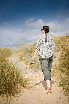 Woman walking to beach in sand dunes