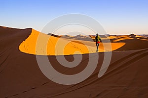 Woman walking on top of a sand dune