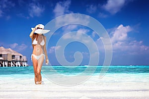 Woman walking in the tropical sea water of a beach at the Maldives islands