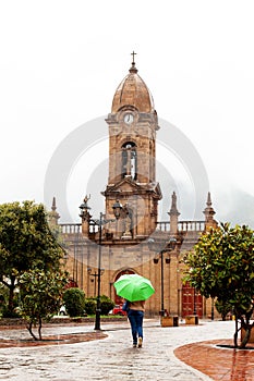 Woman walking with an umbrella at the beautiful central square aof the small town of Nobsa in a rainy day photo