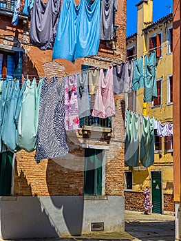 Woman walking under Hanging clothes put to dry on a small traditional street of Venice, Italy. Travel background