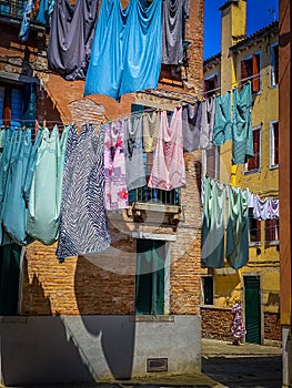 Woman walking under Hanging clothes put to dry on a small traditional street of Venice, Italy. Travel background