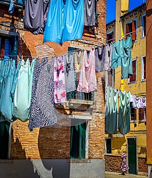 Woman walking under Hanging clothes put to dry on a small traditional street of Venice, Italy. Travel background