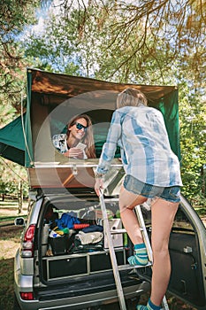 Woman walking up ladder to tent over car