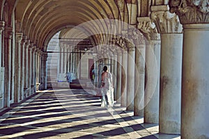 A woman walking Venice arcades during springtime