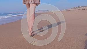 Woman walking on wet sand beach, ocean waves