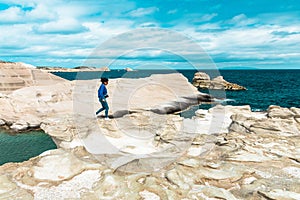 Woman walking on the white cliffs. Sarakiniko, Milos Island, Greece.