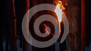 Woman walking in the woods at night time holding a torch