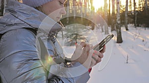 Woman is walking in the woods. Traveler is photographed on the phone in forest. Girl does selfie and communicates with