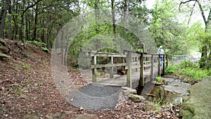 A woman walks across a footbridge through the forest