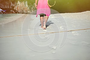 a woman walks along footprints in the sand.