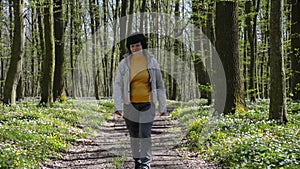 A woman walks along a path in a blooming spring forest