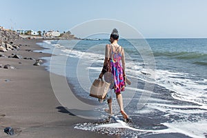 Woman walks on the beach with shopping