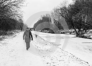 A woman walks down the frozen canal towpath