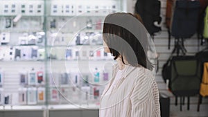 A woman walks through an electronics store and chooses her purchases. Modern smart gadgets in a big store