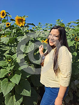 Woman walks through a field of sunflowers full of happiness in fullness, with tranquility, relaxation, calm, peace and splendor