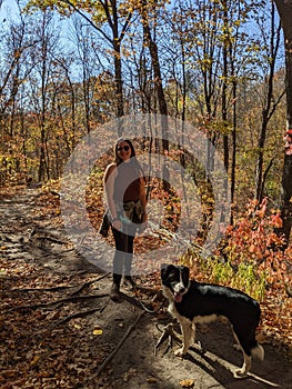 A woman walks her dog in a fall Forest