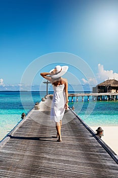 Woman walks over a wooden jetty in the Maldives