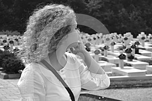 A woman walks past a multitude of graves in the cemetery, black and white photo