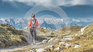 A woman walks on a path in the mountains