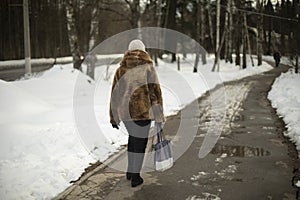 Woman walks on road. Girl in winter in city. Snow in park
