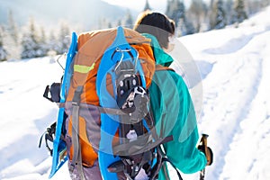 A woman walks with snowshoes on the backpack in the mountains in winter