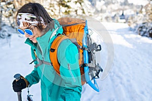 A woman walks with snowshoes on the backpack in the mountains in winter
