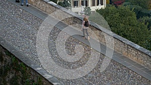 Woman walks on stone cobbles. City of Bergamo.