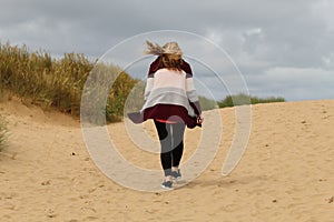 A woman walks through strong winds at Formby Beach in Liverpool