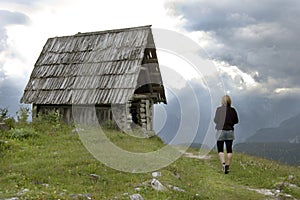 Woman walks to abandoned mountain cottage