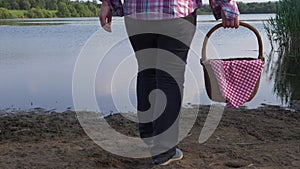 Woman walks towards lake shore vintage picnic basket