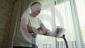 Woman walks on a treadmill in a front of the window