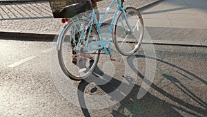 A woman walks a vintage bicycle across a road