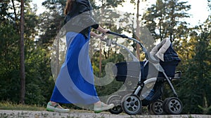 Woman walks whith stroller in the forest in slow motion.