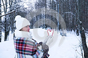 A woman walks through the winter forest, she holds candy canes in her hands.