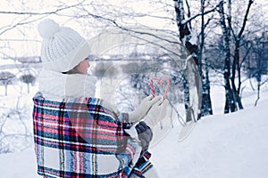 A woman walks through the winter forest, she holds candy canes in her hands.