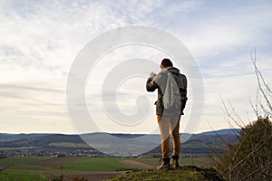 Woman wanderer on a rock takes picture of view